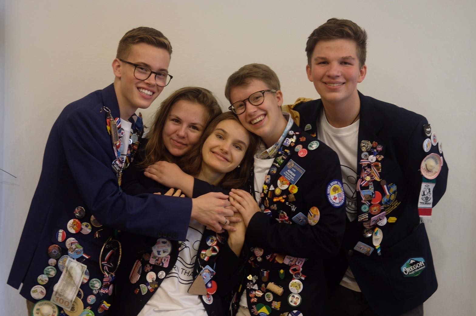 Lucy and her exchange friends hugging in Rotary Youth Exchange jackets